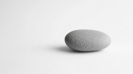 A solitary smooth gray stone rests on a minimalistic background, symbolizing tranquility and simplicity, perfect for wellness or artistic themes.の素材