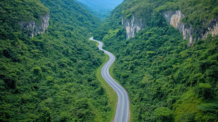 A breathtaking view of a winding road nestled within a lush green valley surrounded by mountains, offering a perfect setting for travel and exploration.の素材