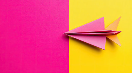 A vibrant paper airplane crafted from colorful paper sits against a bright pink and yellow backdrop, symbolizing creativity and playful innovation.の素材