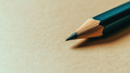 A close-up view of a sharpened pencil resting on a brown paper surface, showcasing its fine tip and wooden texture, ideal for art or education themes.の素材