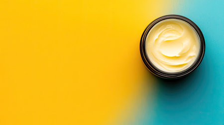 Cream sits in a sleek black jar on a vibrant yellow and blue background. Perfect for beauty and skincare themes, showcasing natural products.の素材