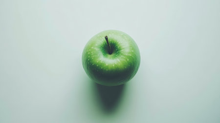 A fresh green apple sits on a smooth surface, showcasing its vibrant color and natural beauty. Ideal for health, food, and wellness themes.の素材