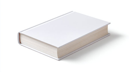 This blank hardcover book features a pristine white cover, angled on a clean surface. It serves as a versatile template for designers and creators.の素材