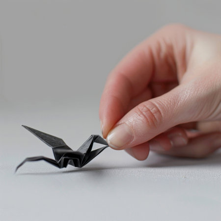 This image showcases a delicate hand holding a black origami crane, emphasizing creativity and artistry with a minimalist aesthetic and a soft focus background.の素材