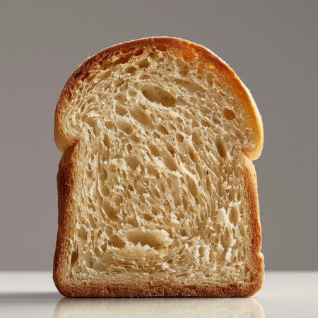 A close-up view of a slice of freshly baked bread showcasing its soft texture and golden crust. Perfect for food-related projects or culinary themes.の素材