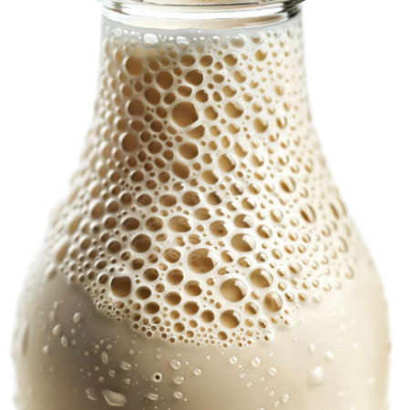 A clear glass bottle filled with creamy milk showcases a foamy surface and numerous bubbles, perfect for highlighting freshness and nutrition in beverage photography.の素材