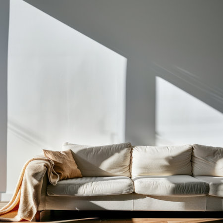 Bright and inviting living room featuring a cream sofa and a soft throw blanket. Natural light floods in through large windows, creating a serene atmosphere perfect for relaxation.の素材