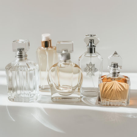 A refined display of five unique perfume bottles, each showcasing distinct shapes and styles on a bright surface, captured in soft natural light for a serene aesthetic.の素材