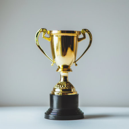 A shiny golden trophy sits on a clean surface, representing triumph and recognition in various competitions, emphasizing achievements in different fields.の素材