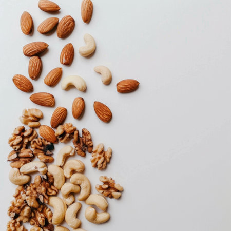 A vibrant assortment of various nuts including almonds, cashews, walnuts, and pecans, beautifully arranged on a clean white surface, highlighting healthy snacking options.の素材