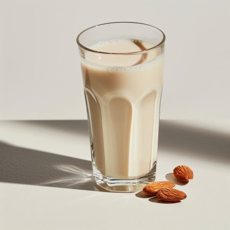 A refreshing glass of creamy almond milk sits elegantly on a light surface, accompanied by whole almonds, creating a perfect dairy-free beverage option for health enthusiasts.の素材