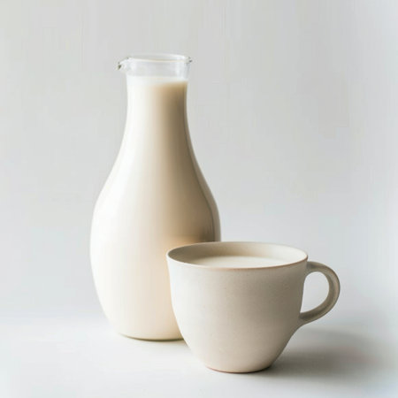 This elegant image showcases fresh milk in a glass bottle paired with a ceramic cup, set against a minimalist backdrop, highlighting themes of health and culinary delight.の素材
