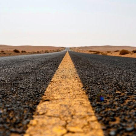 A long, straight road vanishes into the horizon in a serene desert landscape, featuring warm light and a sense of solitude, ideal for travel or adventure themes.の素材