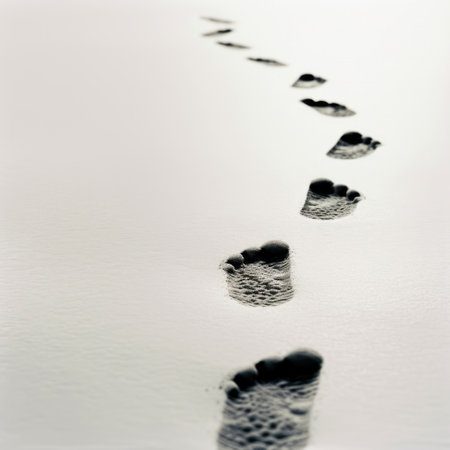 A tranquil beach scene showcases footprints etched in soft sand, leading towards calm waters beneath a gently glowing sky. This serene image evokes peace and relaxation.の素材