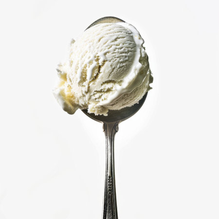 A close-up view of a creamy vanilla ice cream scoop on a silver spoon against a pure white background, ideal for showcasing delicious desserts and treats.の素材