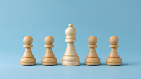 A striking image featuring a central king chess piece surrounded by four wooden pawns on a solid blue background, symbolizing strategy and leadership in play.の素材