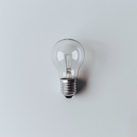 A clear light bulb rests against a smooth grey background, symbolizing innovation and energy, ideal for various creative and commercial applications.の素材
