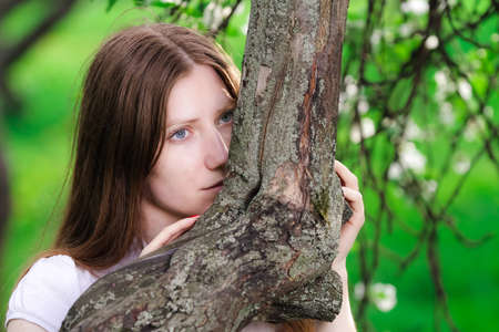 thoughtful beautiful young women embraces tree の写真素材