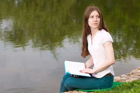 beautiful girl reading book on the bankの写真素材