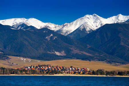 Lake and village at Tatras mountains and white peaks aboveの写真素材