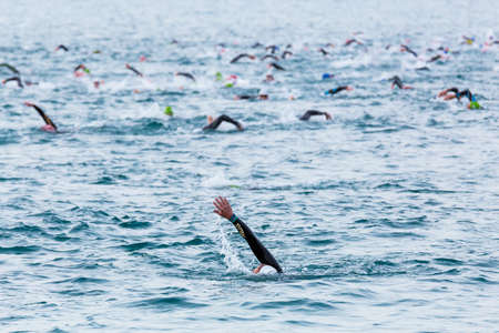 Triathletes swim on start of the Ironman triathlon competition at Calella beachの写真素材