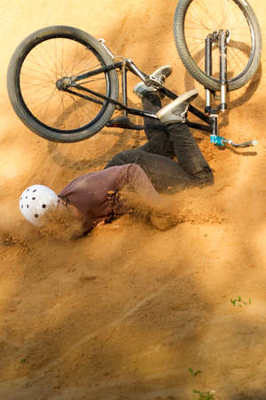 biker is falling from his mountain bike to the sand at the contestの写真素材