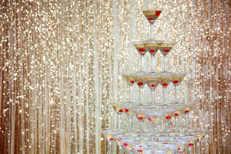 Sparkling champagne pyramid, tower of glasses at the party in front of golden wallの写真素材