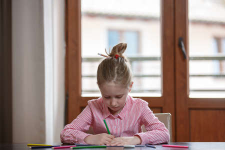 Close up of cute blond hair school girl boring and tired looking up, sitting at the desk with school...