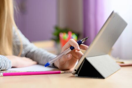 Home-based online training. School at home. Children's hand controls the tablet. Blurred background.の写真素材