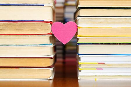 A small heart hangs between two piles of old books.の写真素材