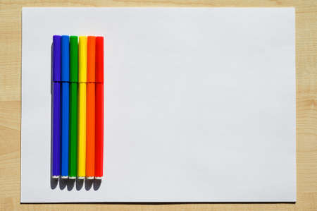 White sheet of paper on a wooden table. Felt pens with rainbow colors and LGBT flag on a blank sheet.の写真素材