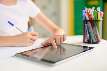 The student's hand controls the tablet. Online home training.の写真素材