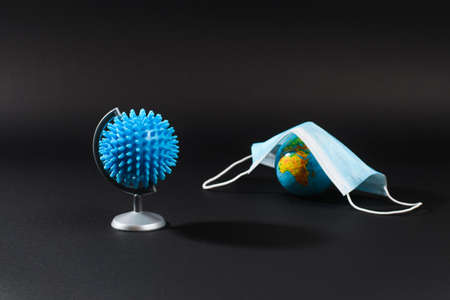 Globe in the form of the Covid-19 virus on a black background. In the background there is a balloon...