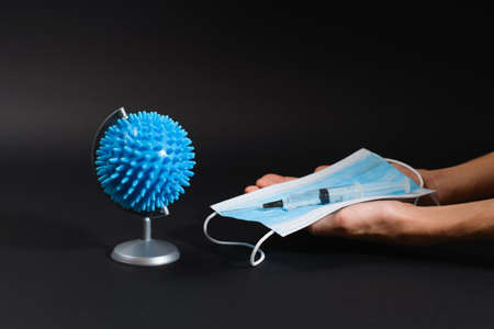 Globe Coronovirus Shape Black Background. Syringe Vaccine Medical Mask Human Hands. Covid-19 rescue...