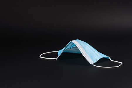 Medical mask in the form of the roof of the house on a dark background. The concept of protecting people from the virus using medical masks.の写真素材