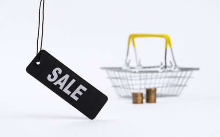 Black label with a large inscription Discounts on the background of an empty shopping basket and stacks of coins. The concept of the sale of goods with big discounts.の写真素材