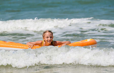joyful girl floats on the sea waves on an inflatable mattressの写真素材