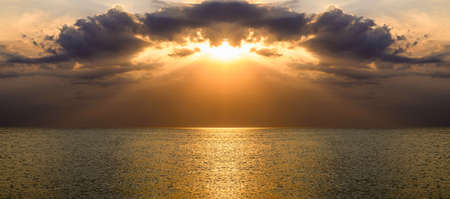 Sunset panorama over the sea surface. Orange sky with clouds.の写真素材