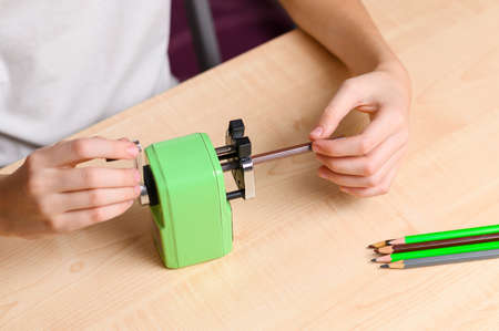 A student sharpens pencils with a sharpener. View from above. Focus on pencil and hand.の写真素材