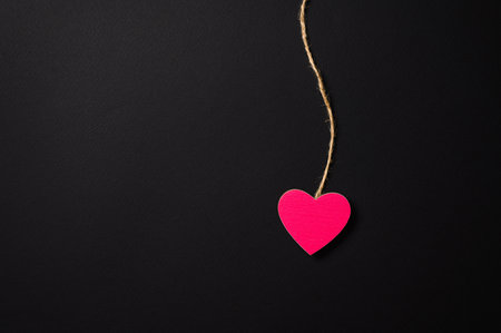 Pink small heart on a string on a dark background. There is a free empty space. Valentine's day greeting conceptの写真素材
