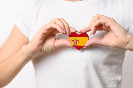 Love Spain. The girl holds a heart in the form of the flag of Spain on her chest. Spanish patriotism conceptの写真素材