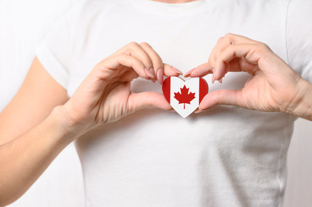 Love Canada. The girl holds a heart in the form of the flag of Canada on her chest. Canadian patriotism conceptの写真素材