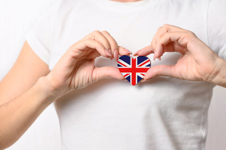 Love Great Britain. The girl holds a heart in the form of the flag of Great Britain on her chest. British patriotism conceptの写真素材