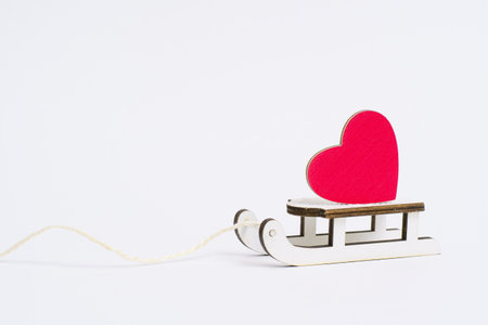 Small red heart on small wooden sleds on a white background. Valentine's day conceptの写真素材