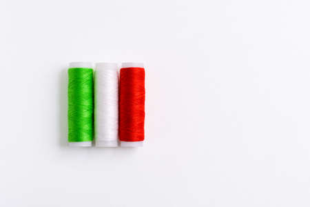 Three spools of thread for sewing are stacked in the form of the flag of Italy on a white background. Concept of Italian patriotism and the country's garment industry. There is a free empty space.の写真素材