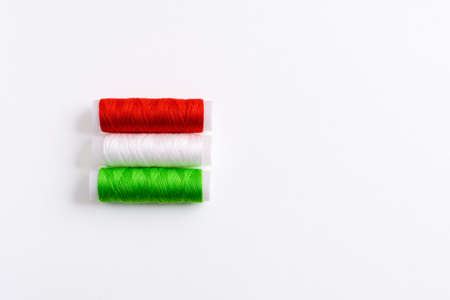 Three spools of thread for sewing are stacked in the form of the flag of Hungary on a white background. Concept of Hungarian patriotism and the country's garment industry. There is a free empty space.の写真素材