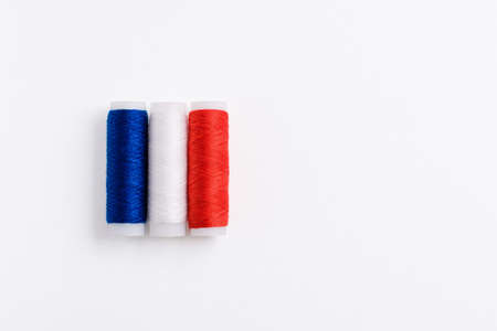 Three spools of thread for sewing are stacked in the form of the flag of France on a white background. Concept of French patriotism and the country's garment industry. There is a free empty space.Three spools of thread for sewing are stacked in the form of the flag of France on a white background. Concept of French patriotism and the country's garment industry. There is a free empty space.の写真素材