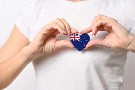 Love New Zealand. The girl holds a heart in the form of the flag of New Zealand on her chest. New Zealand concept of patriotismの写真素材