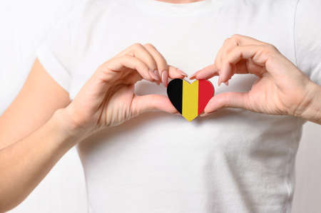 Love Belgium. The girl holds a heart in the form of the flag of Belgium on her chest. Belgian patriotism conceptの写真素材