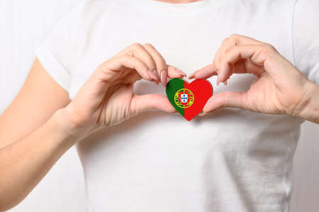 Love Portugal. The girl holds a heart in the form of the flag of Portugal on her chest. Portuguese patriotism conceptの写真素材